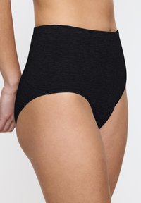 Hoge taille zwarte naadloze onderbroek, gemaakt van zachte stof met een gladde textuur en een eenvoudig ontwerp. Geen zichtbare patronen of accenten.