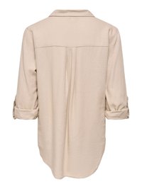 Beige long-sleeve shirt with rolled cuffs, back pleat detail, and curved hem, shown from the back.