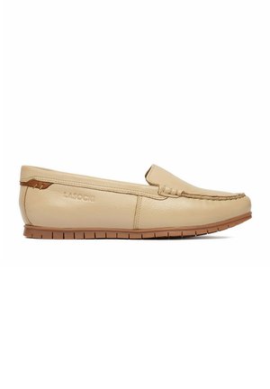 Mocassino slip-on in pelle beige con suola in gomma marrone e cuciture visibili lungo la punta, progettato per un uso casual.