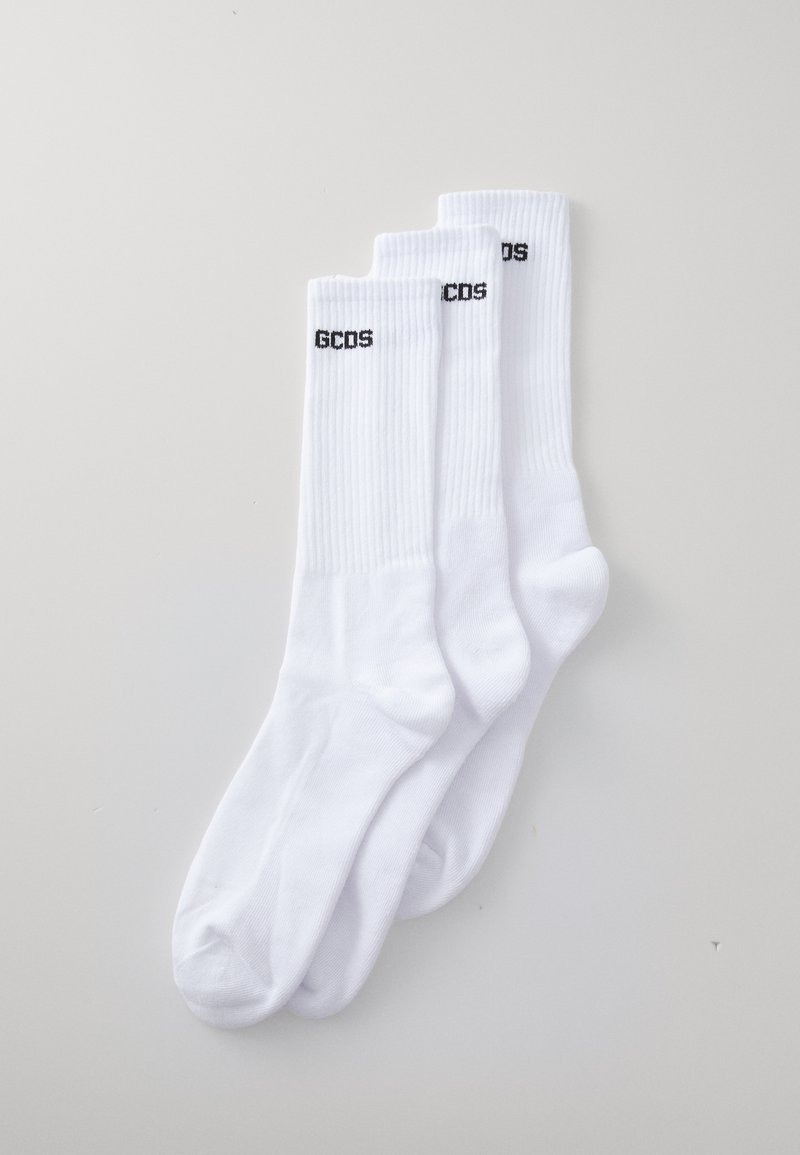 Chaussettes en coton blanc avec des bords côtelés et une impression du logo "GCOS" en noir. Trois paires empilées sur un fond gris clair.