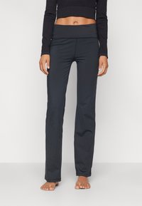 Black athletic pants with a wide, folded waistband, smooth fabric, and a fitted silhouette, designed for comfort and flexibility.