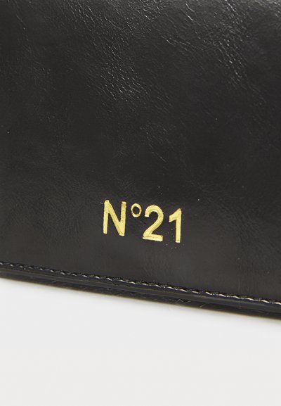 Borsa in pelle nera con texture, caratterizzata da un logo dorato "N°21". Il dettaglio mostra il punto di cucitura lungo i bordi e una superficie liscia e morbida.