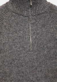 Primo piano di maglione grigio lavorato a maglia con collo alto a coste e zip centrale argentata parzialmente aperta.