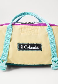 Columbia kottääbi omaduseks on kollane kangas, mille ülaosa on lilla, teal'ist detailidega, kaks käepidet ning logomärk. Tekstuuriga pind ja tõmblukud.
