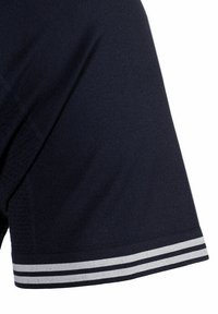 Polo de color azul marino con mangas cortas, una tela texturizada y un borde a rayas blanco y gris en los puños.