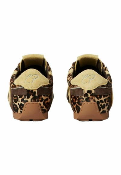 Un par de zapatillas con estampado de leopardo y lengüetas de ante beige bordadas con "CP," mostradas desde atrás sobre un fondo blanco.
