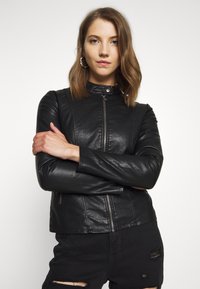 Black leather jacket with a high collar, zip closure, and fitted design. Smooth texture and minimal accents enhance its sleek appearance.