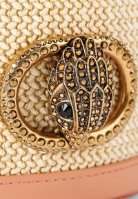 Geweven straw handtas met een goudkleurige decoratieve sluiting met zwarte accenten en strass-details, aangevuld met een zachte perziklederen afwerking.