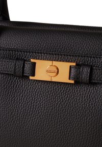 Black leather handbag featuring a textured surface, gold-toned hardware, and a prominent clasp with a circular logo detailing.