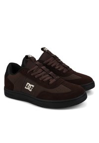 Ein Paar dunkelbraune Low-Top-Sneaker mit schwarzen Sohlen, Mesh-Zungen und weißem DC-Logo an den Seiten und auf den Zungenlaschen.