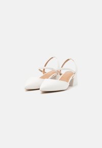White pointy-toed shoes with a low block heel and an adjustable ankle strap. Made of smooth material with a matte finish.