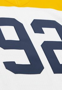 Weißes Sporttrikot mit großer marineblauer Nummer 92, die auf die Vorderseite gestickt ist, und einem gelben Kragen entlang der oberen Kante.