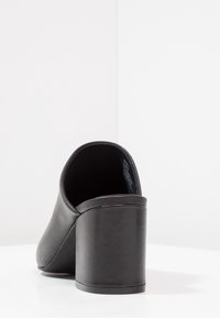 Zwarte open-hak schoenen met een ronde neus en een robuuste blokhak. Glad leren textuur zonder zichtbare patronen of accenten.