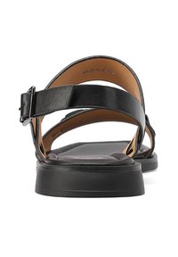 Sandali di pelle nera con soletta piatta, cinturino regolabile con fibbia e decorazioni minime. Presentano una superficie liscia e un design robusto.