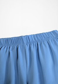 Modrá látka s naťahovacím elastickým pásom, zobrazenie textúry a detailov šitia na bielom pozadí.