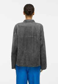 Ciemnoszara skórzana kurtka o luźnym kroju, z szerokim kołnierzem i widocznym przeszyciem. Charakteryzuje się gładką fakturą i lekko oversize'owym fasonem.