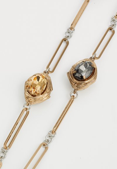 Gold-tone necklace featuring two oval gemstones: one amber and one smoky grey. Links are elongated and mixed metal, with a textured finish.