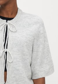 Γκρι ανοιχτό μπεζ ζακέτα με κοντά μανίκια, κατασκευασμένη από απαλό ύφασμα, με υφή στην επιφάνεια και ρυθμιζόμενο κορδόνι στη λαιμόκοψ η.