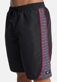 Μαύρα μαγιό σορτς με ελαστική μέση, κορδόνι και πλαϊνές καρό λεπτομέρειες σε μπλε, γκρι και κόκκινα στοιχεία· περιλαμβάνει μικρή λεπτομέρεια με λογότυπο.