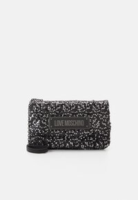 Paillettet svart clutch-veske med teksturert overflate. Har en logoplater og en avtagbar stropp for allsidighet. Kompakt rektangulær form.