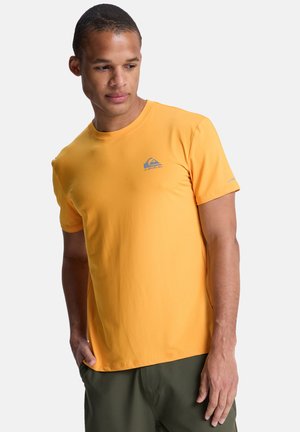 Żółta koszulka z krótkim rękawem wykonana z gładkiej tkaniny, z małym szarym logo na lewej piersi i okrągłym dekoltem.