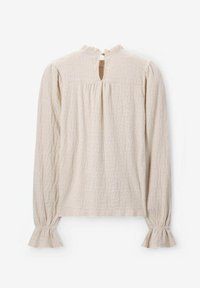 Beige top met lange mouwen, een gestructureerd patroon, ruches aan de mouwen en een keyhole-opening aan de achterkant, met een hoge hals.