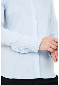 Blue and white striped blouse with a classic collar, button-down front, and ruffled cuffs. Made from lightweight fabric.