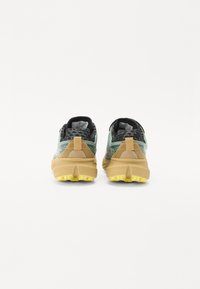 Sporty running shoes with a textured mesh upper in green and black, a beige midsole, and a yellow rubber outsole.