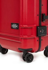 Red hard-shell suitcase with a textured finish, black hardware, four wheels, and an integrated combination lock. Features Eastpak logo.