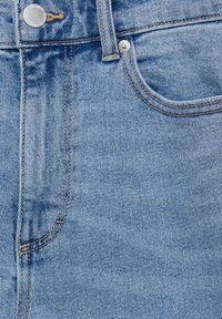 Light blue denim jeans featuring a smooth texture, five-pocket design, brass button hardware, and contrast stitching along the seams.