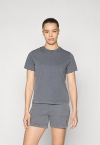 T-shirt en coton gris avec un col rond et des manches courtes, associé à un short gris rayé avec un petit logo.