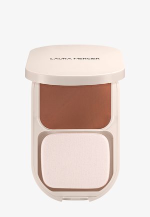 Compactpoeder met een lichtbeige verpakking, bevat een donkerbruine poeder bovenop en een witte sponsapplicator eronder, met een gladde textuur.
