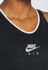 Black athletic tank top with a white logo featuring "NIKE" and "AIR." Thin white band around the neckline with repeated text detail.