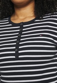 Zwart-wit gestreept longsleeve shirt met een henley-halslijn, voorzien van zes knopen aan de voorkant en een klein logo op de borst.