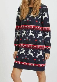 Robe pull de Noël tricotée avec une base bleu marine, motifs de rennes et flocons de neige en blanc, rouge et accents blancs, avec des poignets côtelés.
