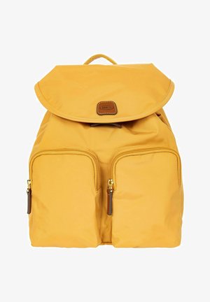 Sac à dos jaune avec deux poches zippées à l'avant, tirettes de fermeture éclair en cuir, rabat supérieur et petite pièce en cuir avec le nom de la marque "BRICS" sur le devant.