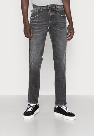 Mörkgrå jeans med rak passform, som har fram- och bakfickor, subtila blekningar och kontrasterande sömmar, kombinerade med svarta sneakers.