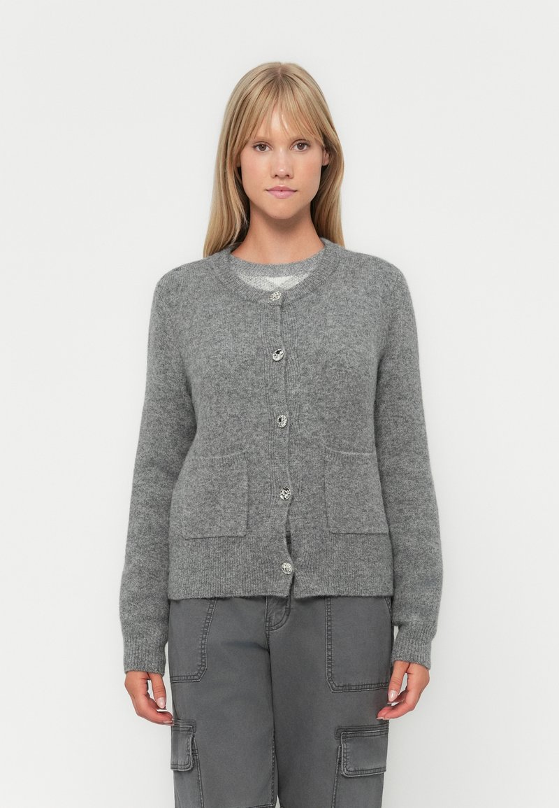 Grå strikket cardigan med rund hals, knapplukking, to frontlommer og myk tekstur. Stylet med grå cargo bukser.
