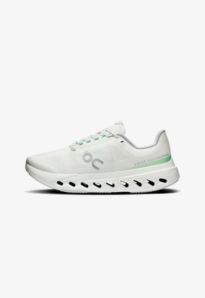 Weißer Laufschuh mit Mesh-Obermaterial, grünen Akzenten und silbernem Logo. Verfügt über eine dicke, gepolsterte Sohle mit Ausschnitten zur Belüftung.