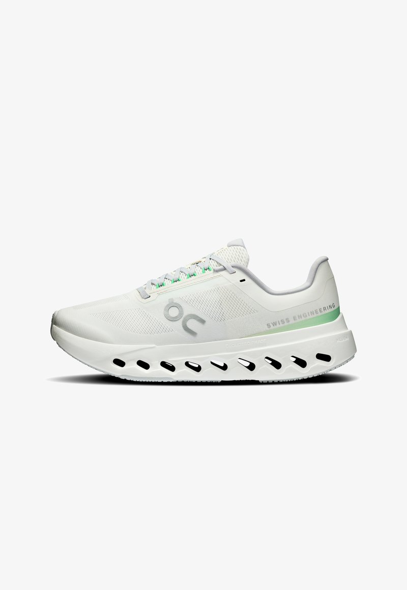 Baskets de course blanches avec tige en mesh, accents verts et logo argenté. Comprend une semelle épaisse et rembourrée avec des découpes pour la ventilation.