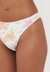 Fehér virágmintás bikinialsó, pasztell virágokkal és finom függőleges bordázott textúrával. Rugalmas szélek és alacsony derék dizájn.