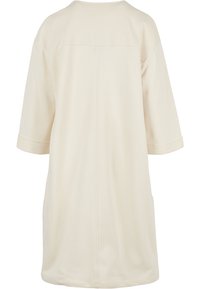 Cream-colored tunic with short rolled sleeves, a straight fit, back seam details, and side pockets. Soft cotton-blend material.