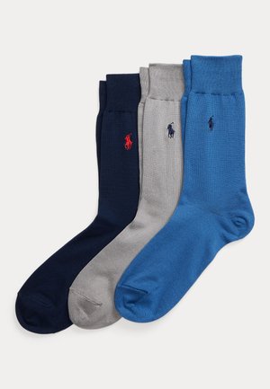 Trois paires de chaussettes de sport de couleur marine, gris clair et bleu, chacune ornée d'un petit logo brodé représentant un joueur de polo près du bord-côte.