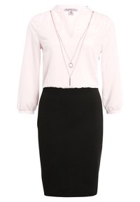 Ljust rosa blus med lång ärm och v-ringning, matchad med en figursydd svart pennkjol. Inkluderar en lager på lager silverkedjanhalsband.