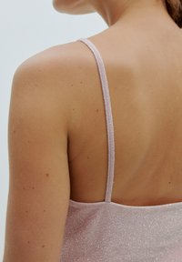 Helles rosa, ärmelloses Kleid mit dezentem Glanz. Schlanke Träger und ein tief ausgeschnittenes Rückendesign, mit glatter Textur und minimalistischem Stil.