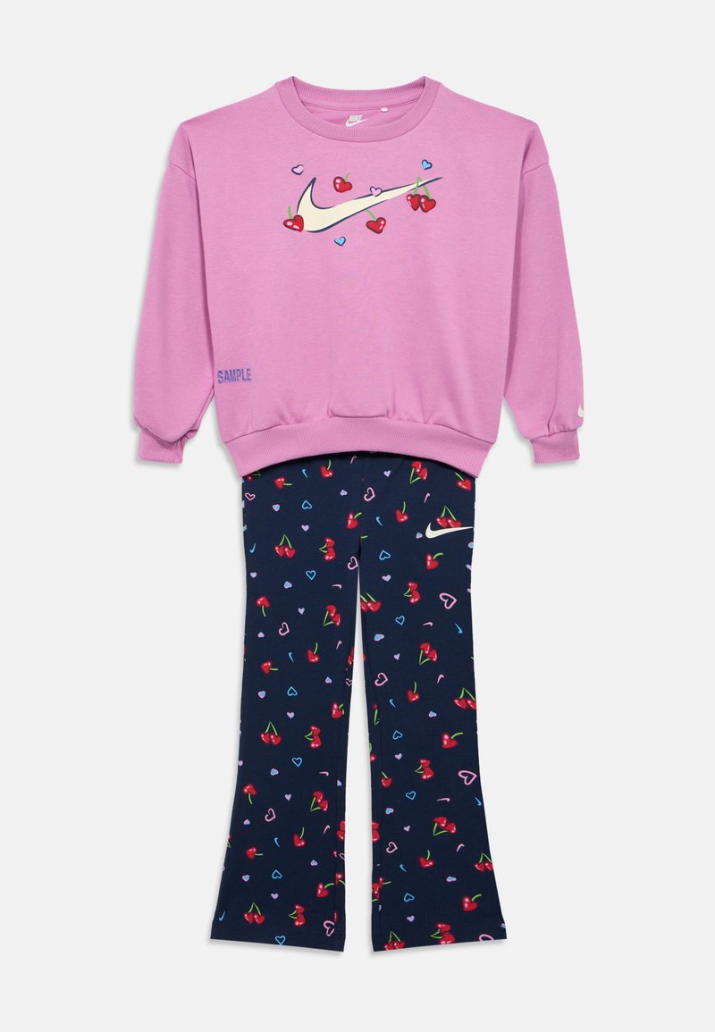 Ροζ φούτερ Nike με γραφικά κερασιών και καρδιών, συνδυασμένο με σκούρο μπλε παντελόνι με μοτίβα κερασιών και καρδιών.