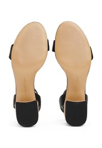Sandales à talons hauts noires avec dessus lisse, design à bout ouvert, et semelle texturée portant une marque au talon.