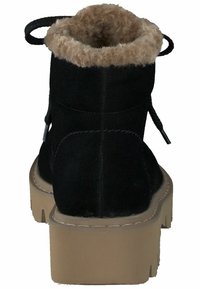 Botín de ante negro con un cuello de pelo sintético color marrón, forma redonda, suela gruesa de plataforma beige y un lazo decorativo en la parte trasera.