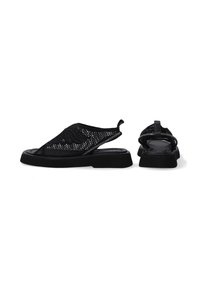 Černé síťované slip-on boty s texturovaným vzorem, měkkou vnitřní podšívkou a silnou gumovou podrážkou. Mají zádovou pásku pro podporu.