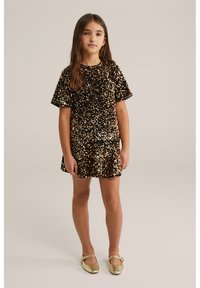 Czarna i złota sukienka z cekinami, z krótkimi rękawami, dopasowanym stanikiem i rozkloszowanym dołem. Złote buty na paski dopełniają stylizację.